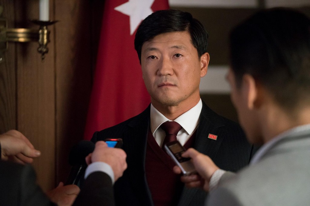 Le Président Kim (Tom Choi) face à la presse