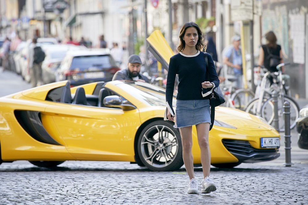 Dana Gerçan dans la rue et un homme vers sa voiture jaune 