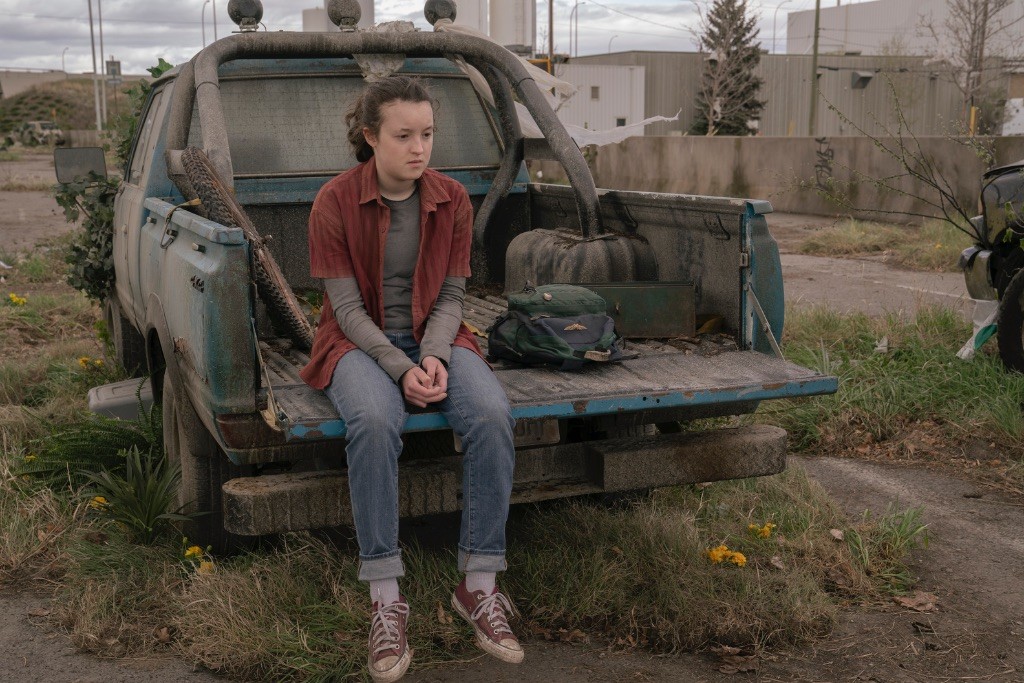 Ellie est assise à l'arrière d'une voiture abandonnée