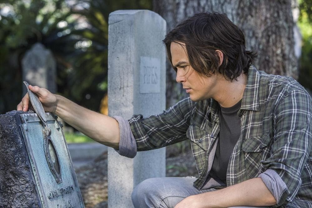 Caleb (Tyler Blackburn) regardent une ancienne tombe à son nom au cimetière de Ravenswood.