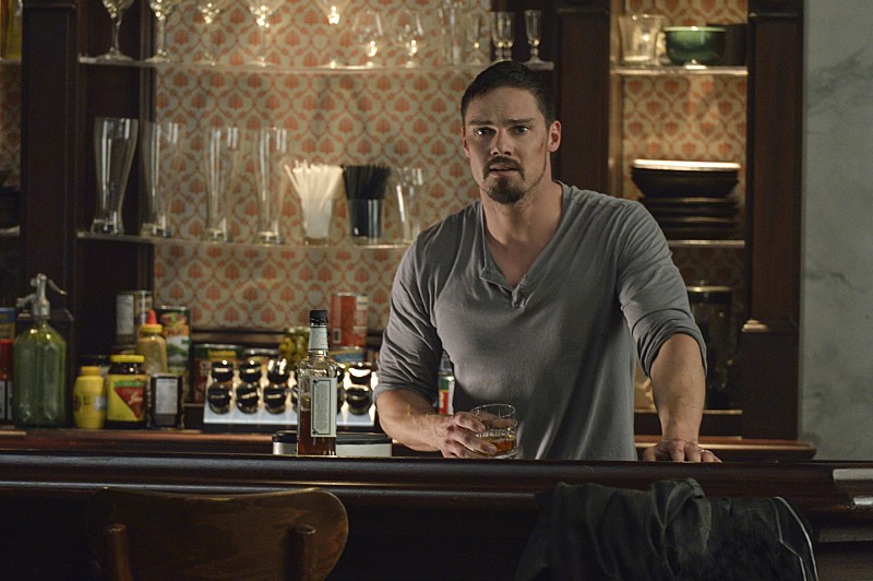 Vincent (Jay Ryan) derrière le bar, un verre à la main