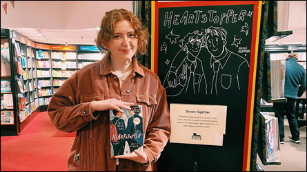 Image d'Alice tenant un livre Heartstopper dans une librairie